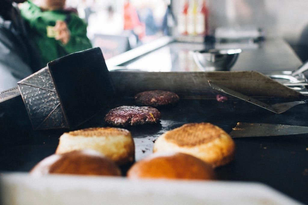 Burger patties and buns toasting on a flat-top griddle
